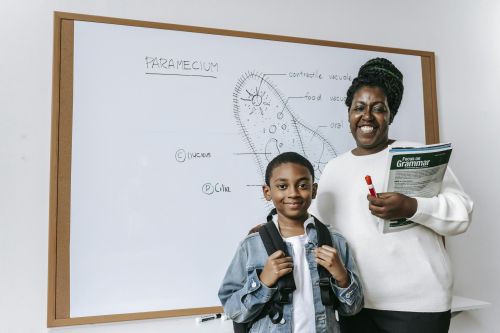 Smiling teacher and student in classroom studying science with a whiteboard.